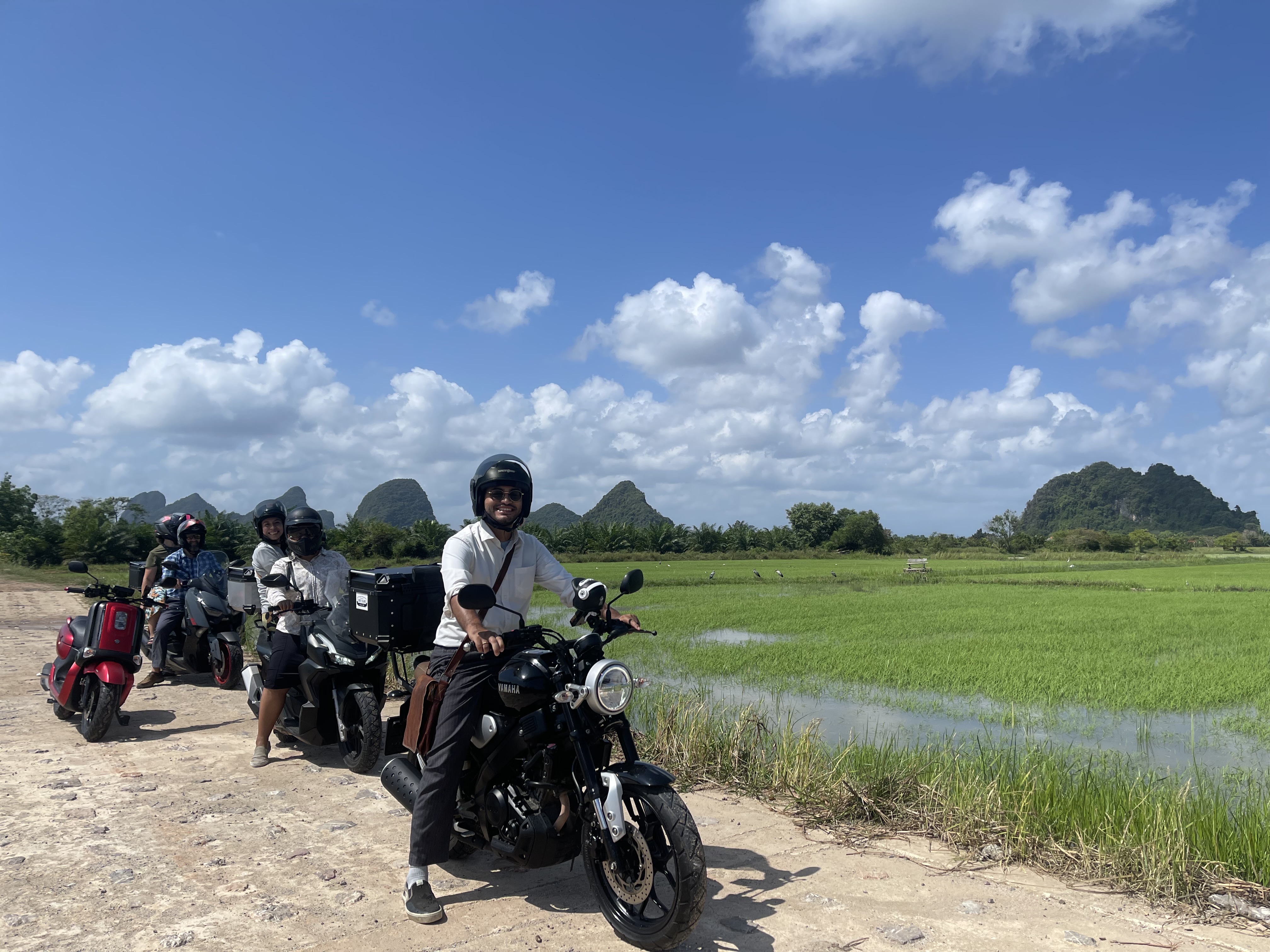 Friends on motorbikes beside vivid rice fields